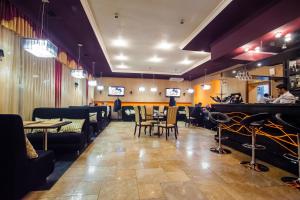 a restaurant with tables and chairs and a piano at Sweet Hall Hotel in Krasnodar