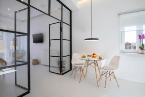 een eetkamer met witte muren en een tafel en stoelen bij Twins Idola Apartments in Pula