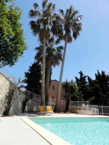 a swimming pool with palm trees and two chairs at Residence Dei Fiori in Pietra Ligure