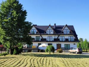 a large house with a car parked in front of it at Pokoje nad Dunajcem in Biały Dunajec