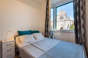 a bedroom with a bed and a window with a church at Apartment Oliveto Sibenik in Šibenik