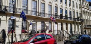 a red car parked in front of a building with flags at Andorra Guest Accommodation in Brighton & Hove