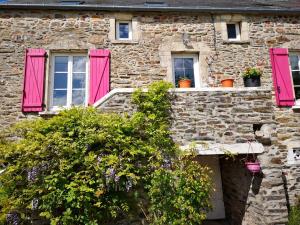 un edificio de piedra con persianas rosas y flores en Au Domaine de Sophie piscine chauffée couverte et jacuzzi couvert, en Crasville