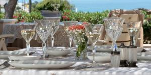 PosidhoníaにあるDellaGracia Mansion in Poseidonia Syrosのワイングラスと皿、花のテーブル
