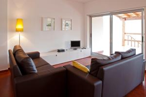 a living room with two leather couches and a television at Gondoriz-House in Terras de Bouro