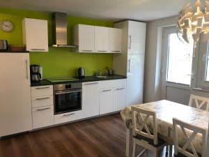 RottorfにあるFerienwohnung Forstwegのキッチン(白いキャビネット、ダイニングテーブル付)