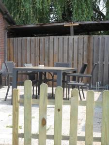 a wooden fence with a table and chairs in a backyard at Hoeveheikant Vakantiewoningen in Lage Mierde