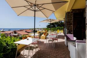 a patio with tables and chairs and umbrellas at Mare Lughente in S'archittu Cuglieri