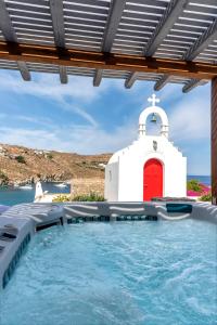 una capilla y una piscina con puerta roja en Etesians Suites & Villas, en Playa Super Paradise