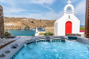 eine Kirche mit einem Pool vor einer Kapelle in der Unterkunft Etesians Suites & Villas in Super Paradise Beach