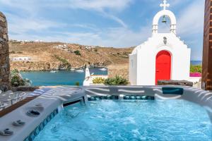 una chiesa con piscina di fronte a una cappella di Etesians Suites & Villas a Super Paradise Beach