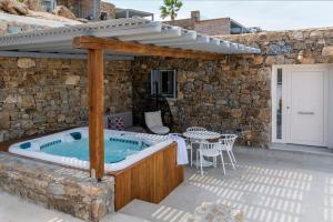 un patio con bañera de hidromasaje y pared de piedra en Etesians Suites & Villas en Super Paradise Beach