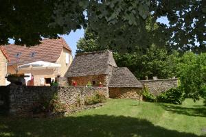 a stone building in a yard next to a house at La Clef des Champs in Saint-Léon-sur-Vézère
