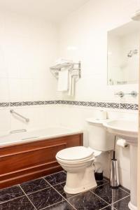 uma casa de banho com um WC, uma banheira e um lavatório. em Lynhams Hotel em Laragh