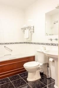 a bathroom with a toilet and a tub and a sink at Lynhams Hotel in Laragh