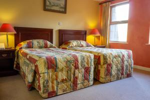 twee bedden naast elkaar in een hotelkamer bij Lynhams Hotel in Laragh