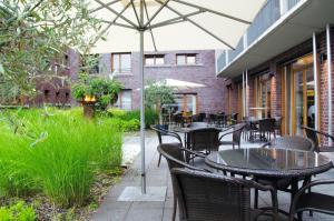 an outdoor patio with tables and chairs and an umbrella at Hotel Begardenhof in Cologne