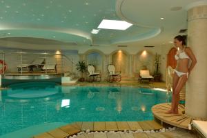 a woman standing on a bench next to a swimming pool at Hotel Alle Alpi in Moena