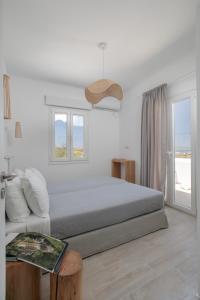 a white bedroom with a bed and a window at Naxos Infinity Villa and Suites in Naxos Chora