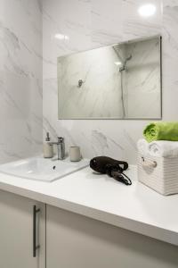 Baño blanco con lavabo y espejo en PaulMarie Apartments on Gogolya 39, en Babruisk