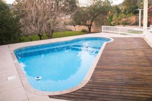 a swimming pool with a wooden deck next to a house at Casa Boutique Requinte e Aconchego in Pomerode