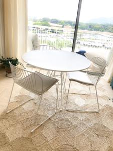 una mesa y sillas blancas en una habitación con ventana en JACARANDA II Appartement, en Mandelieu-la-Napoule