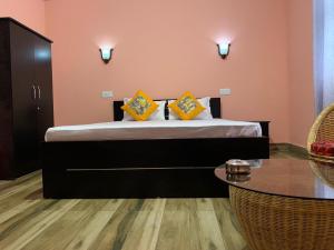 ein Schlafzimmer mit einem Bett mit gelben Kissen und einem Tisch in der Unterkunft Kitsel Homestay in Ravangla
