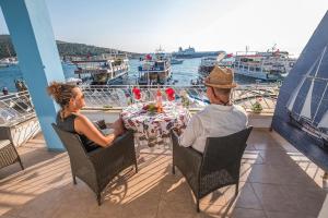 twee personen aan een tafel op een balkon met boten bij Villa Vongole in Çeşme