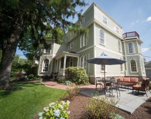 a house with a table and an umbrella in the yard at Serenity Inn Newport in Newport