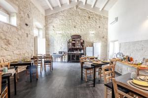 a restaurant with tables and chairs and a stone wall at Giardini Acantus in Rosolini