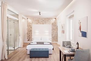 una camera bianca con letto, tavolo e sedie di S&G Corfu Old Town Apartments - The Volto Suite a Città di Corfù