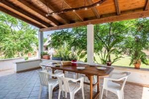 - une table en bois et des chaises blanches sur la terrasse dans l'établissement Villa Rosa zona Torre San Giovanni, à Torre San Giovanni