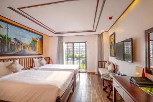 a hotel room with two beds and a table at Fivitel Hoi An Hotel in Hoi An