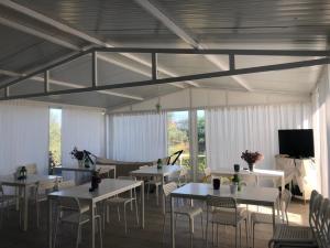 a dining room with tables and chairs and a tv at GIOTA ROOMS in Arkoudi