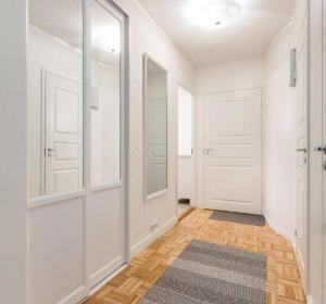 a hallway with two white doors and a rug at Kaunis valoisa 4. krs pikkukaksio Vantaa Koivukylä in Vantaa