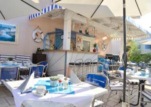 un ristorante con tavoli e sedie bianchi e ombrelloni di Happy Lake by Thomas Strugger a Krumpendorf am Wörthersee