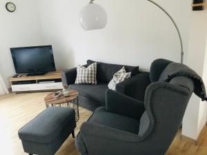 a living room with a couch and a chair and a tv at Liegeplatz TWEE in Laboe
