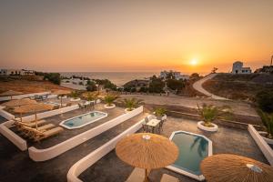 - une vue sur la piscine avec parasols et l'océan dans l'établissement Rhenea Resort, à Imerovigli