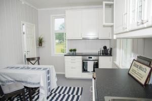 a kitchen with white cabinets and a table in it at lunde slusevaktarbolig in Lunde