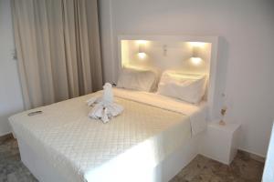 a bedroom with a white bed with a towel on it at Golden Star Praxitelous in Agia Marina Aegina