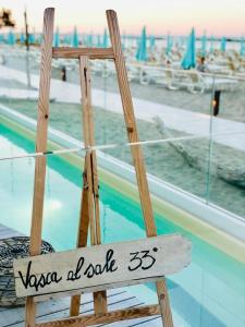 a wooden chair sitting in front of a swimming pool at Hotel Doge in Rimini