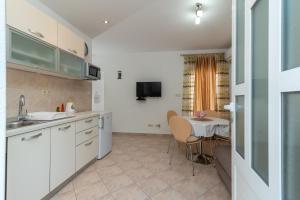 a kitchen with white cabinets and a table in a room at Apartment Nives in Trogir