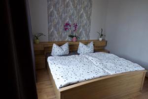 Un dormitorio con una cama con sábanas y almohadas blancas. en Ferienwohnung Kroppenmühle, en Schönburg