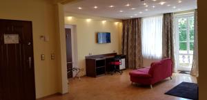 a living room with a red chair and a desk at Hotel-Villa Lalee in Dresden