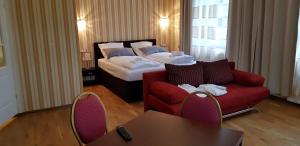 a hotel room with a bed and a red couch at Hotel-Villa Lalee in Dresden