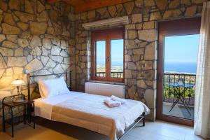 una camera da letto con un letto e un muro di pietra di Villa Oneiro Luxury Home ~ Nature, Serenity, View a Ierápetra