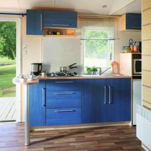 eine Küche mit blauen Schränken und einem Waschbecken in der Unterkunft Mobil home climatisé en Alsace in Biesheim