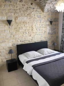 - une chambre avec un lit et un mur en pierre dans l'établissement Le 5B, à Barjac