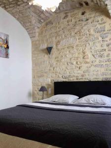 - une chambre avec un mur en pierre et un lit dans l'établissement Le 5B, à Barjac