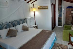 ein Schlafzimmer mit einem großen weißen Bett und einem grünen Stuhl in der Unterkunft Blu Brezza Marine Hotel in Hisarönü